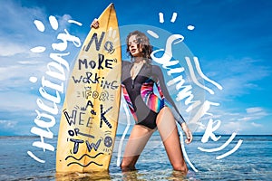 attractive young woman in wetsuit with surfboard posing in ocean at Nusa dua Beach Bali Indonesia