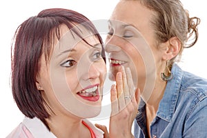 Attractive young woman whispering secret in friend's ear