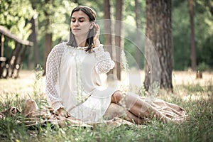 Attractive young woman in a white dress in the forest on the grass