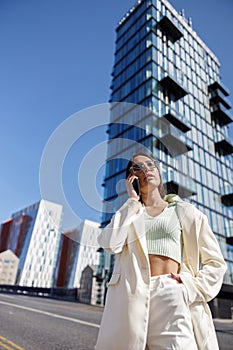 Attractive young woman in white suit calling friend stand near business centre