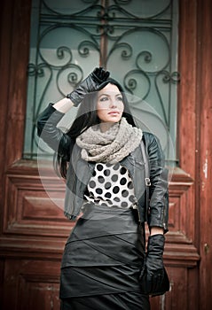 Attractive young woman in winter fashion shot with wrought iron decorated doors in background. Beautiful fashionable female