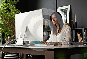 Attractive young woman working at office, using contemporary desktop computer.