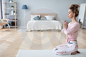 Attractive young woman working out at home, doing yoga exercise on white mat