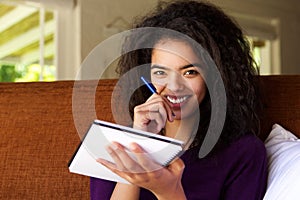 Attractive young woman writing ideas in book