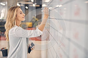 Attractive young woman writing on task board in office