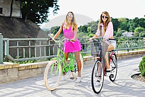 Attractive young women on a bicycles - outdoor fashion portrait