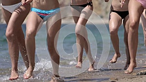 Attractive young women in bikinis running along the shore of the beach