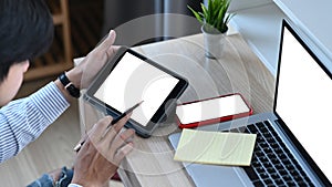 Attractive younng man working with multiple electronic internet devices.