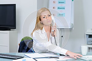 Attraktive woman in office at telephone