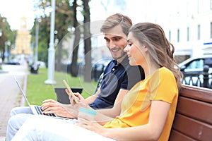 Attrative young couple sitting on a bench and looking something in mobile phone