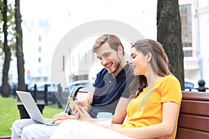 Attrative young couple sitting on a bench and looking something in mobile phone