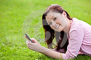 Attrative young pregnant woman texting in a park