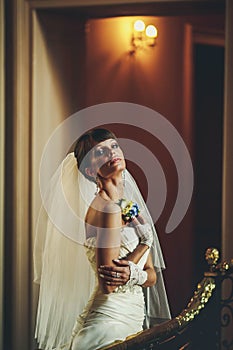 Attrective bride in white dress holding flower and posing