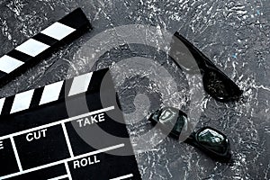 Attributes of film director. Movie clapperboard and sunglasses on grey stone table background top view
