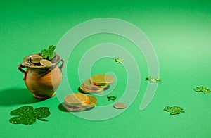 Attributes St. Patrick's Day - a pot of gold stands on a green background, next to it are gold coins and clover leaflets.