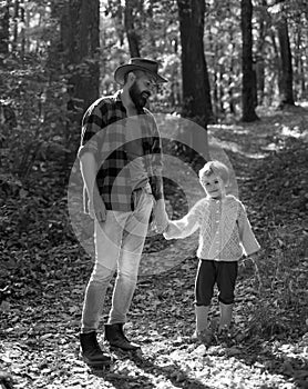 Atumn fun at the park. Both dad and child are laughing. Father and son walking together in the park, fall day.