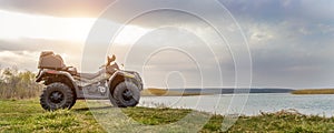 ATV awd quadbike motorcycle pov view near lake or river pond coast with beautiful nature landscape and cloudscape sky