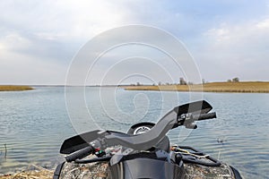 ATV awd quadbike motorcycle pov view near lake or river pond coast with beautiful nature landscape sky background