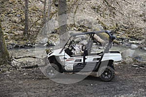 atv awd quadbike with roof and door motorcycle pov view near lake or river coast with nature landscape. forest background.