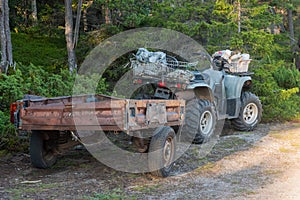 an ATV parked in the woods with an old trailer. travel and tourism