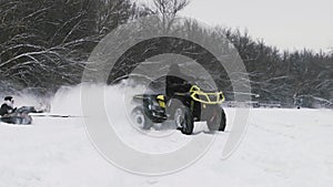 ATV Quad bike drifting on snow. Man on quad bike pulls woman on snowtube on frozen river at winter