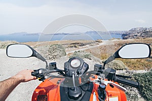 ATV quad bike driving along the shore of Aegean sea on Santorini island, Greece