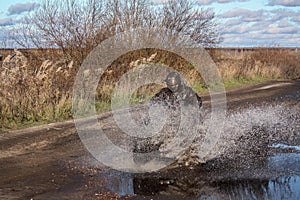 ATV race, dirty road. Uncnown driver in water and mud