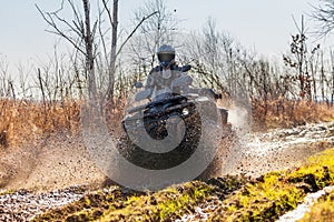 ATV racer drives through mud and water