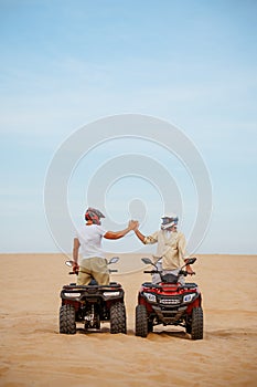 Atv racers in helmets, freedom riding in desert