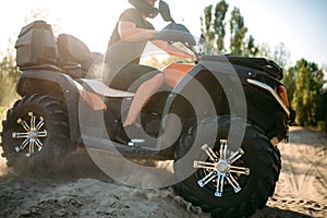 Atv rider in helmet rides on sandy road in forest