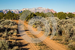 ATV trail through the desert below red and white sandstone cliffs of the Southwest desert