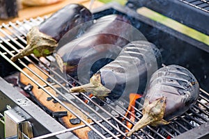 Aubergine on barbecue grill on hot charcoal and fire.