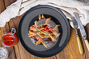 Aubergine penne eggplant pasta, pepper tomatoe sauce, on black plate over wooden table served top view