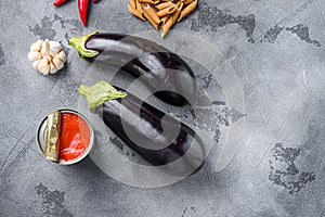 Aubergine penne ingredients eggplant pasta, pepper tomatoe sauce, on grey background top view space for text