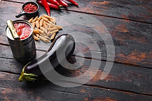 Aubergine penne ingredients eggplant pasta, pepper tomatoe sauce, on old dark wooden table side view space for text