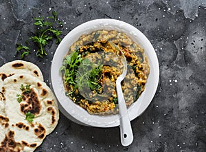 Aubergine spinach vegetarian curry with naan flatbread on a dark background, top view. Indian cuisine