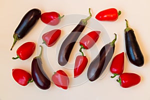 Aubergines and red sweet peppers on beige background