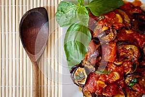 Aubergines in tomato sauce with wooden spoon