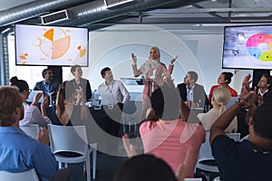 Audience applauding while female speaker speaks in a business seminar