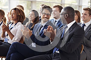 Audience clapping at business seminar, looking at each other