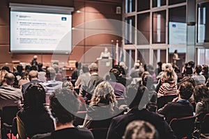 Audience in lecture hall participating at business event.