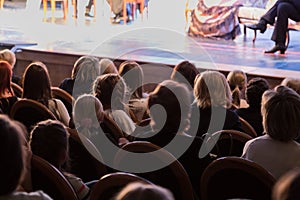 The audience in the theater watching a play. The audience in the hall: adults and children