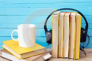 Audio book concept, book and headphones and coffee mug over wood