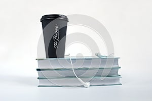 Audio book concept. Headphones, black cup of coffee and stack of books on white background. Copy space for text