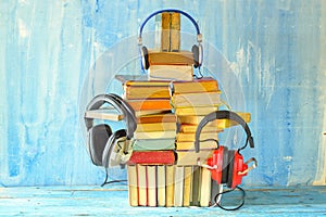 audio book concept with heap of books and set of vintage headphones, grungy background, free copy space