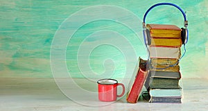 audio book concept with heap of books and vintage headphones, green background, free copy space