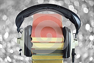 audio book concept with row of books, vintage headphones and bubble balls swirly bokeh