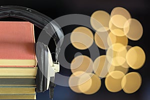 audio book concept with row of books, vintage headphones and bubble balls swirly bokeh