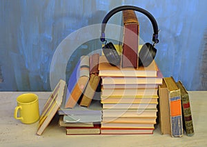 Audio book concept, with stack of books, headphones and cup of coffee