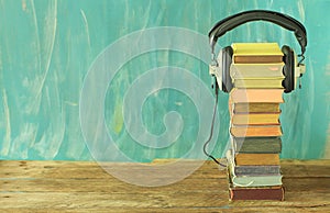 Audio book concept with stack of books and vintage headphones on teal background ,good copy space